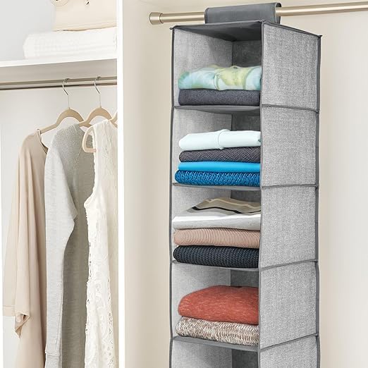 Gray hanging organizer with folded clothes inside, attached to a closet rod.