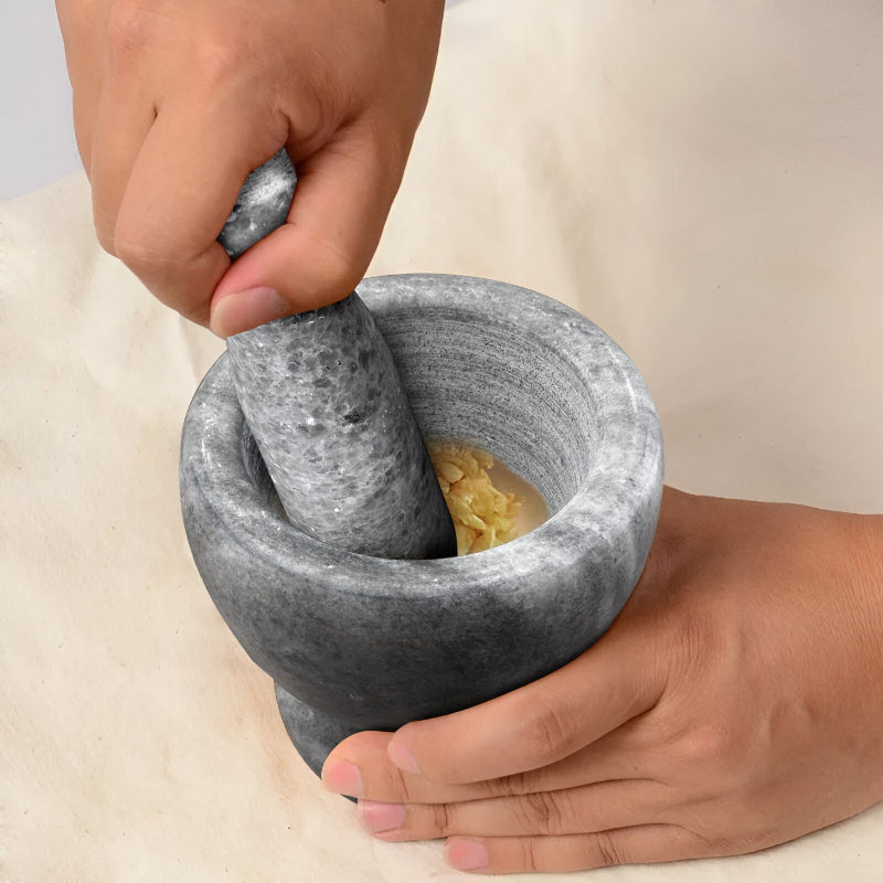 Person using a stone mortar and pestle on a light background