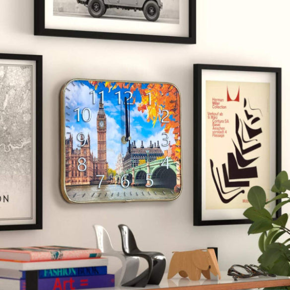 Decorative wall clock with a scenic design, framed pictures, books, and a plant on a shelf.