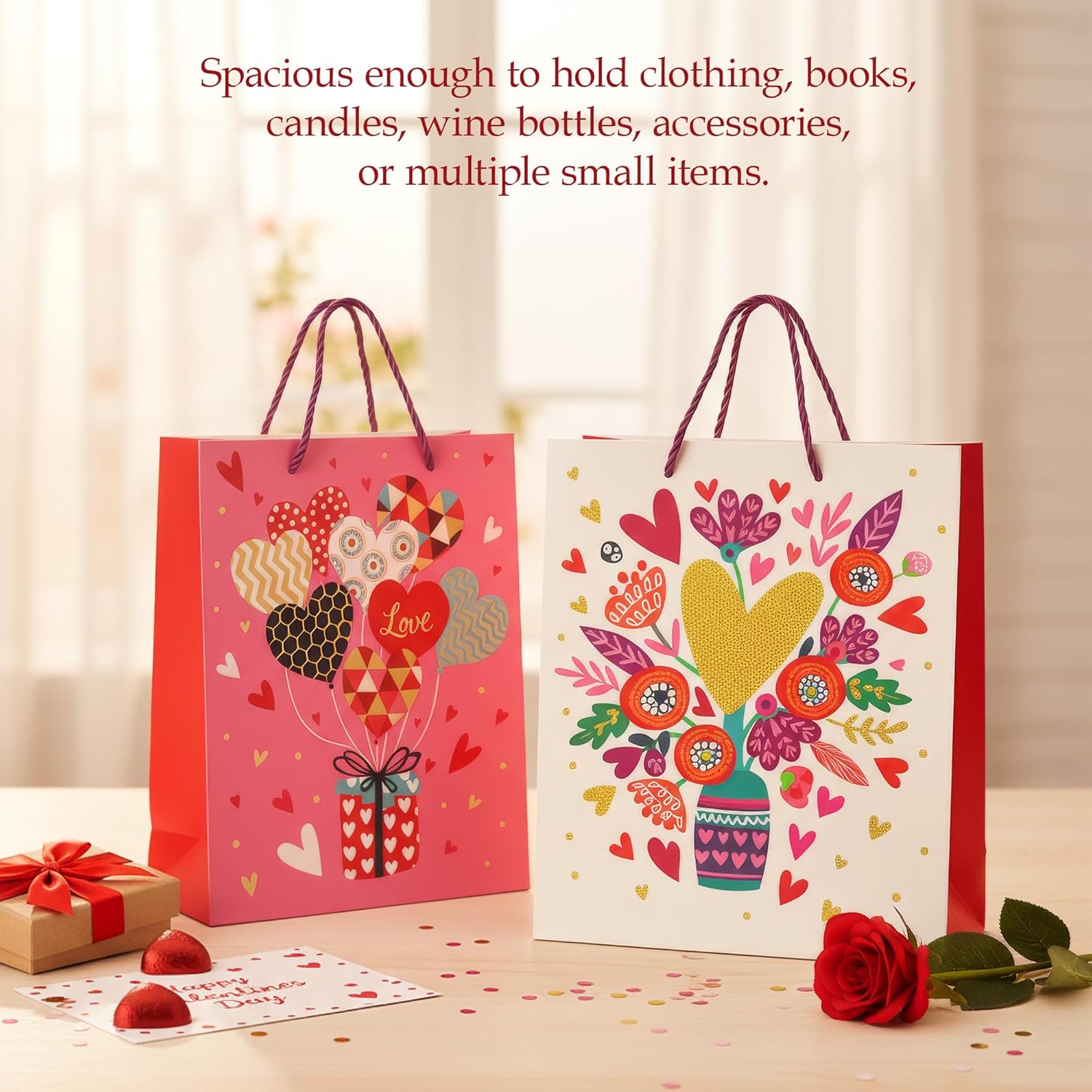 Two decorative gift bags with floral and heart designs on a table with a red rose.