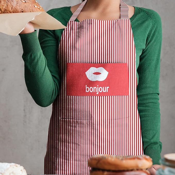 Person wearing a red and white striped apron with 'bonjour' on it, holding a sandwich.