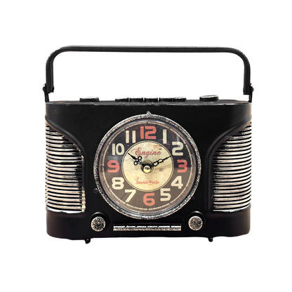 A black vintage-style analog desk clock with a radio design, placed on a wooden table next to a plant and a cup, with the text 'Unique Design' descriptive of its appearance.